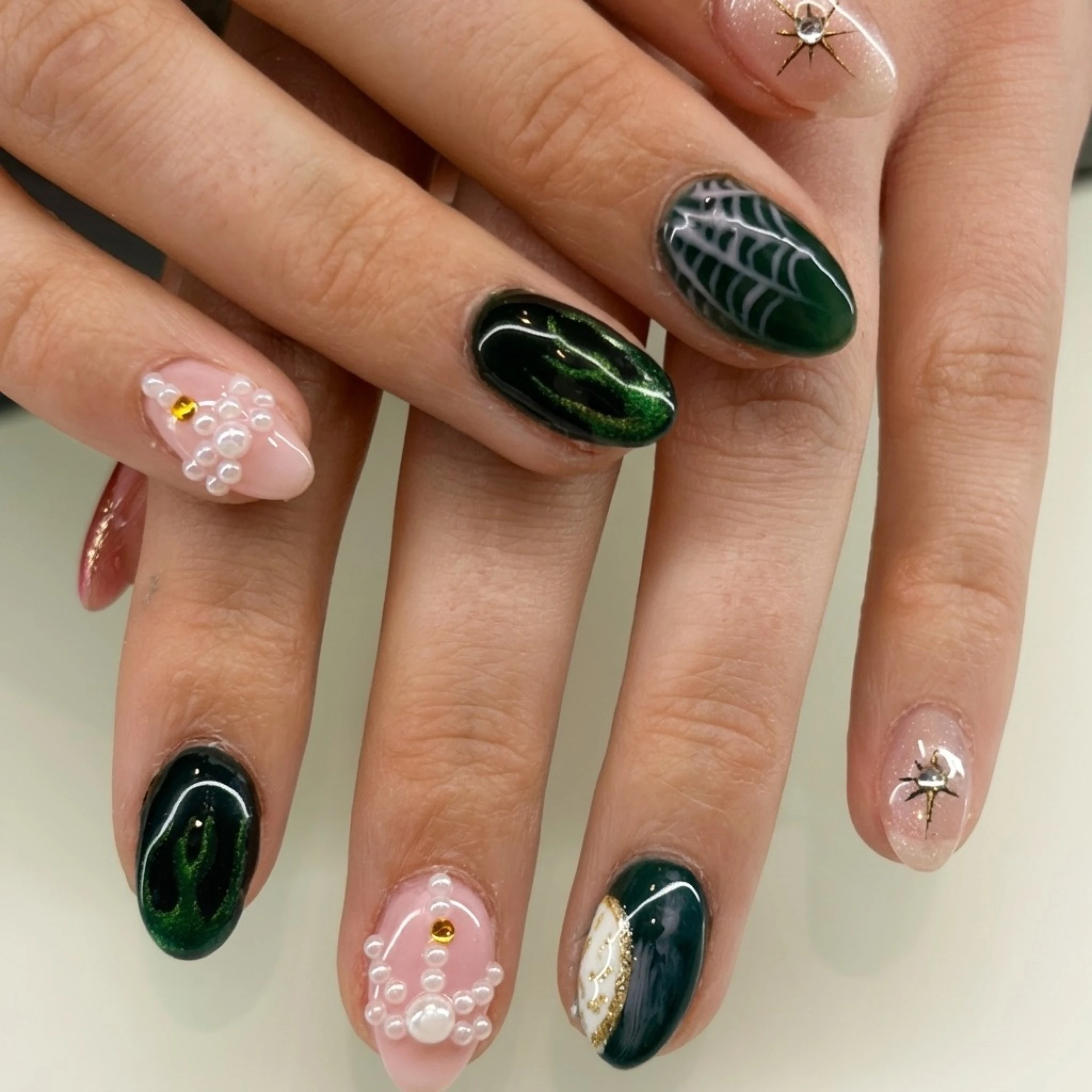 Green and pink mixed nail art with gemstone accents — creative nail design