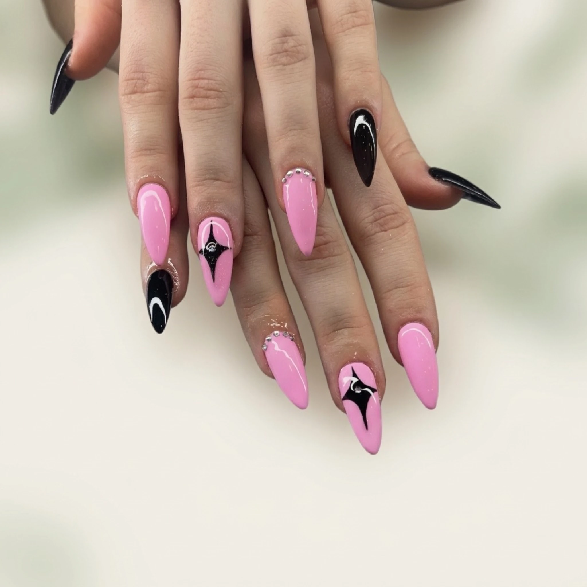 Pink and black stiletto nails with graphic design — bold nail art